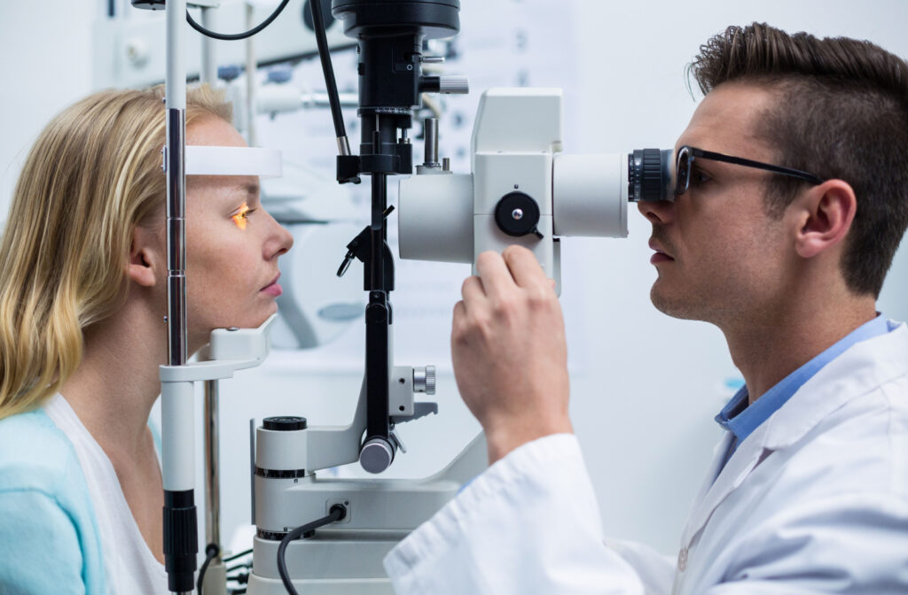 A male optometrist examining the eyes of a young woman using a medical device to detect potential eye problems.