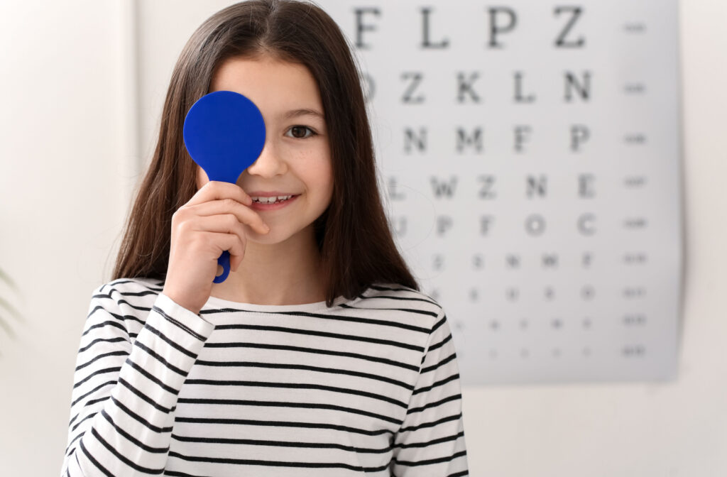 A young girl covering her right eye during a visual acuity examination.