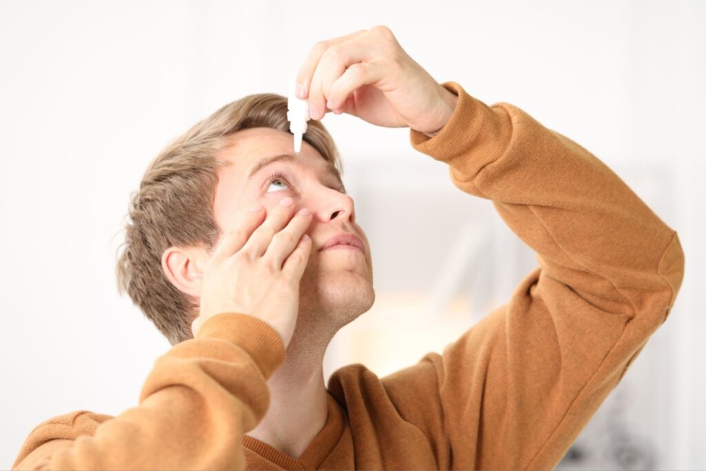 A person looking up as they use a bottle of preservative-free eye drops to sooth their dry eye