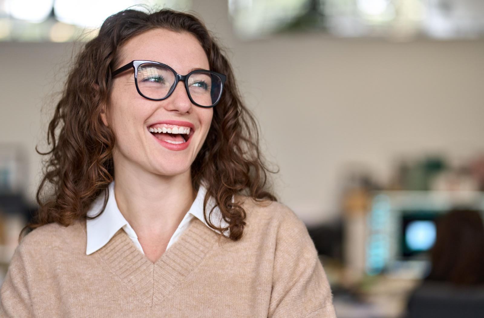 A person wearing thicker rimmed glasses while smiling