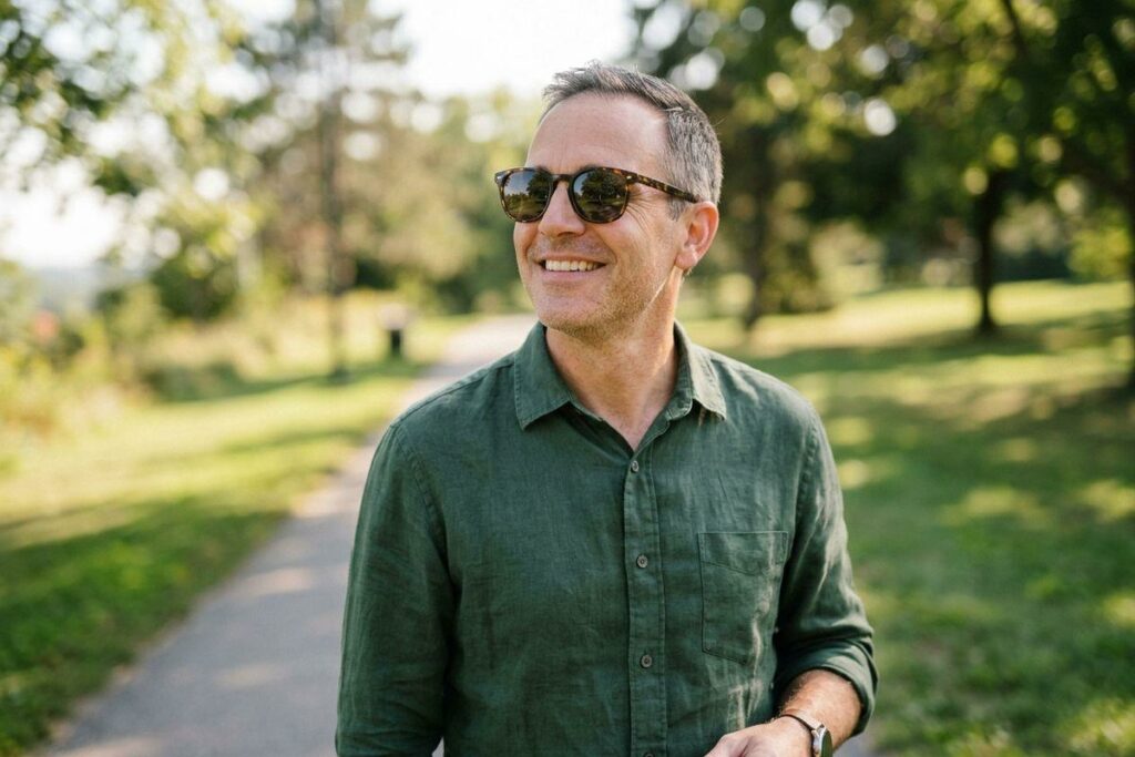 A person wearing prescription sunglasses while smiling outside